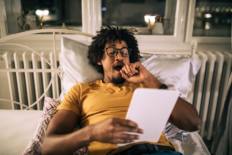 Person yawning in bed, ready to sleep, after taking melatonin