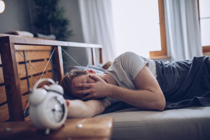 person holding alarm clock in bed
