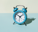An alarm clock against a teal and yellow background. The alarm clock reads 10:08