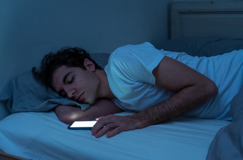 Man falling asleep with phone in bed