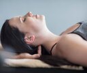 A woman laying face up on a table getting a neck massage.