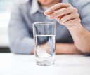 A man dropping an acid reducer into a full glass of water