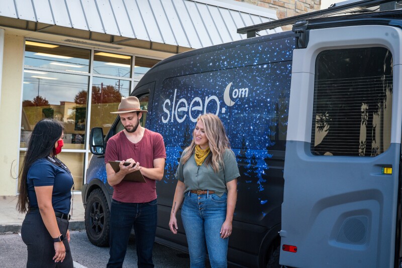 Camper van travellers talk to Mattress Firm Sleep Expert outside of a Mattress Firm store.