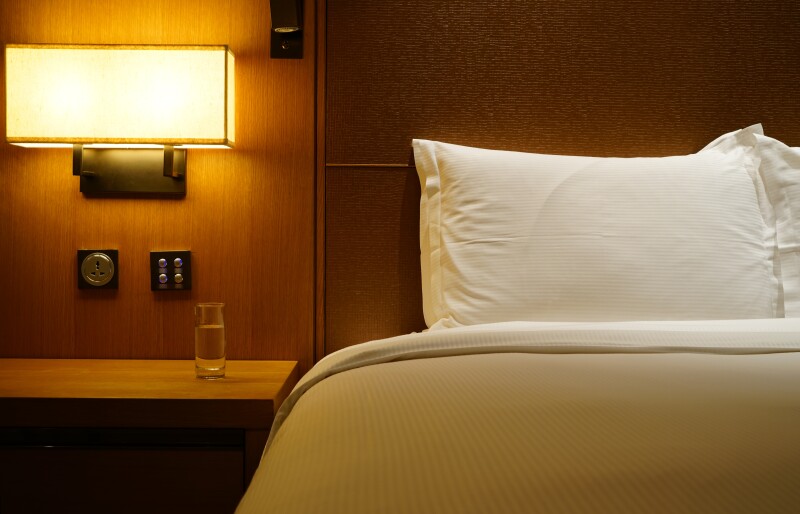 Glass of water on a nightstand next to a hotel bed