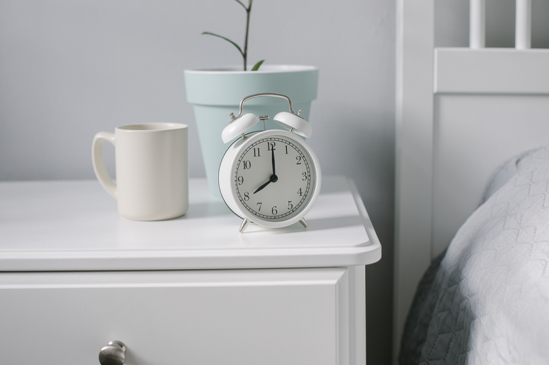 A white clock on a nightstand reading 8 o'clock.