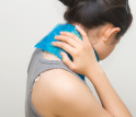 A woman holding an ice pack against her neck.