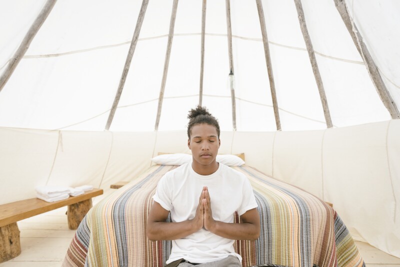 Young man meditating in teepee