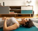 A woman lies on yoga mats and does breathing exercises