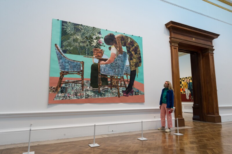 Person in museum looking up at an art piece of two people around a kitchen table.