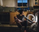 Mom doing laundry while holding baby at night, finishing up chores before bed