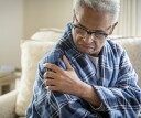Man touching sore shoulder after sleeping on it at night