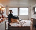 Woman sitting up in bed on a camper van mattress