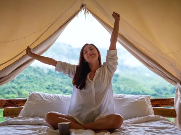 a young woman do stretching after waking up in the morning with a beautiful nature view outside the tent