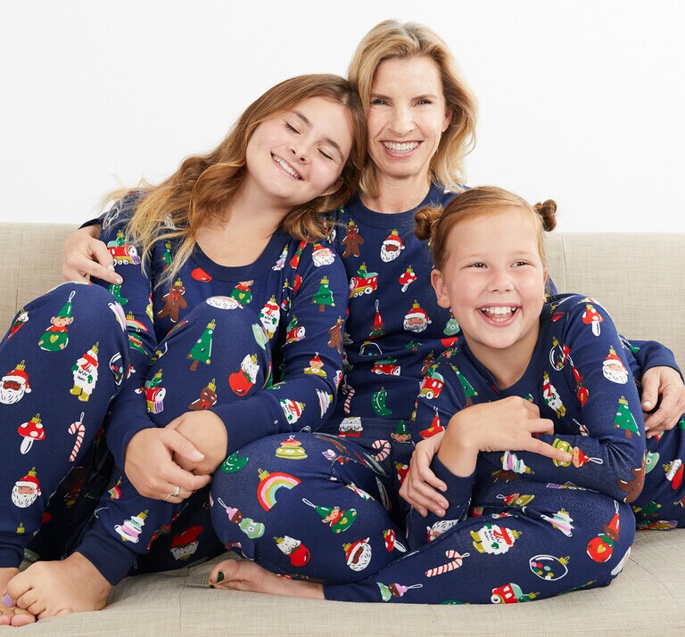 A woman and two young girls laughing in matching Hanna Andersson pajamas.