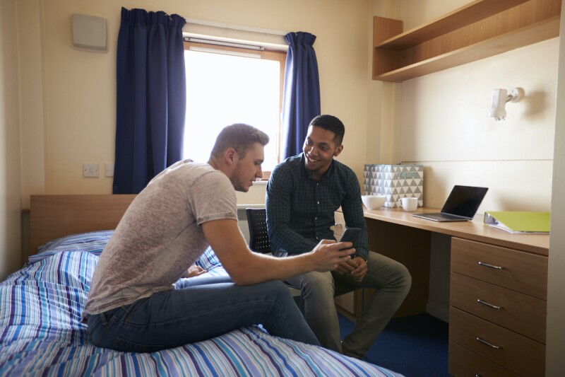 Two roommates in a dorm room talking about sleep schedules