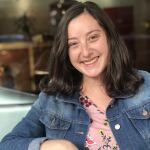 Headshot of writer Casey O'Brien. She has shoulder-length dark brown hair and is sitting in a chair smiling.