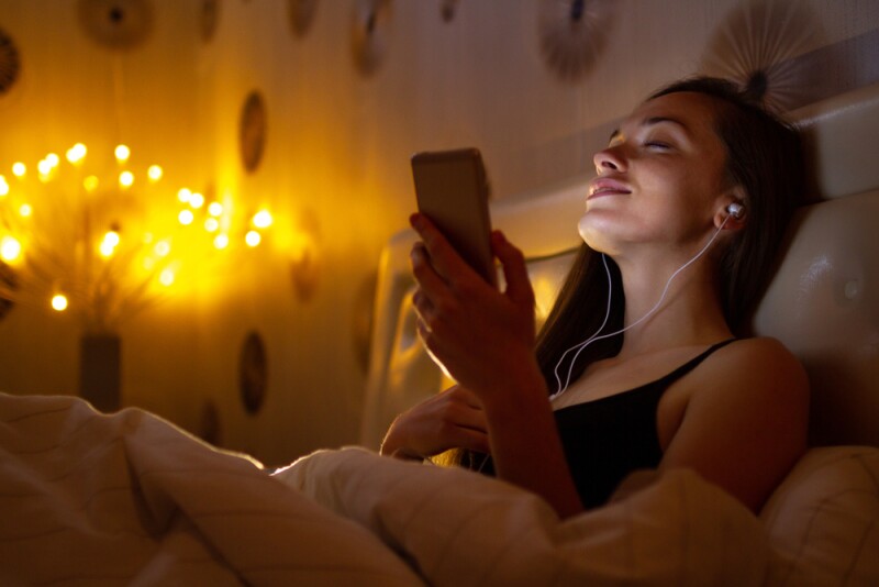 Woman listening to bedtime stories through her phone