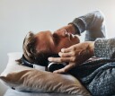 Man resting on bed with headphones on while listening to ASMR