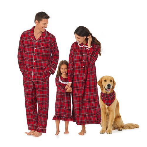 A mother, father, child, and dog pose for a photo while wearing matching, nostalgic Christmas pajamas.