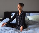 Yoga and Pilates instructor, Alexa Idama, in a calm seated pose, in her bed.