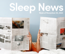Two people sitting up reading newspapers in bed.