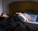 Person covering their face to hide from the sun as they struggle to wake up