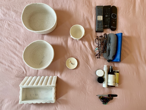 Various woven baskets with commonly used nighttime items such as lip balm, remotes, and glasses.