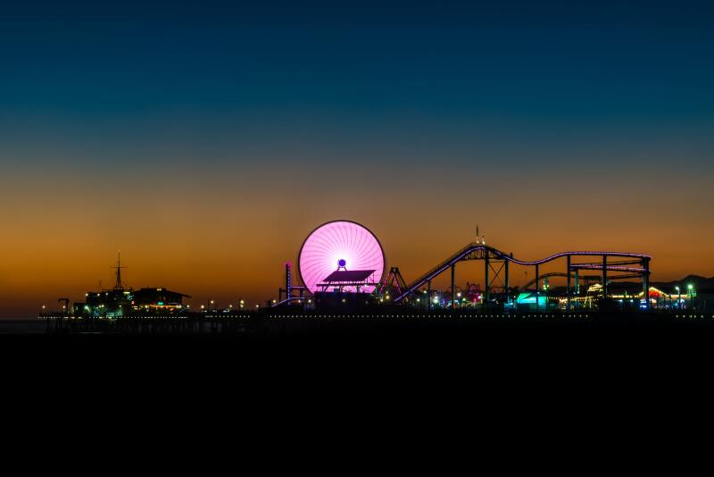 Long exposure shot of a pink ferris wheel at night, in an amusement park