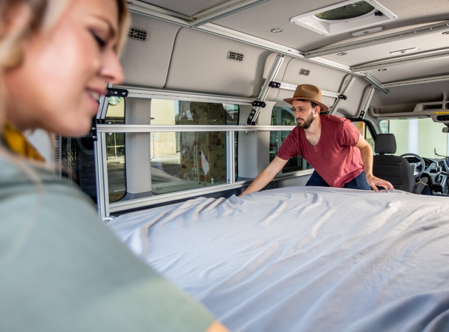 Man and a woman make their camper van bed.
