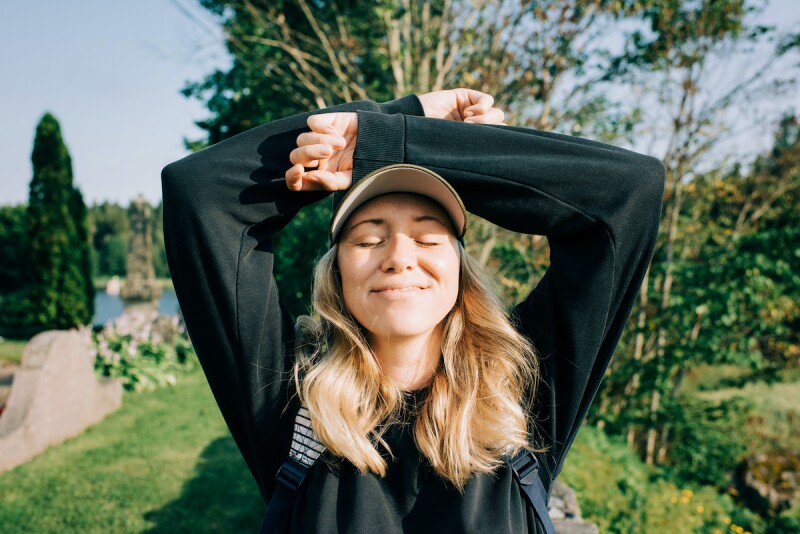 Person wearing sun protection clothing, such as hats and long sleeves, while enjoying the sun's rays